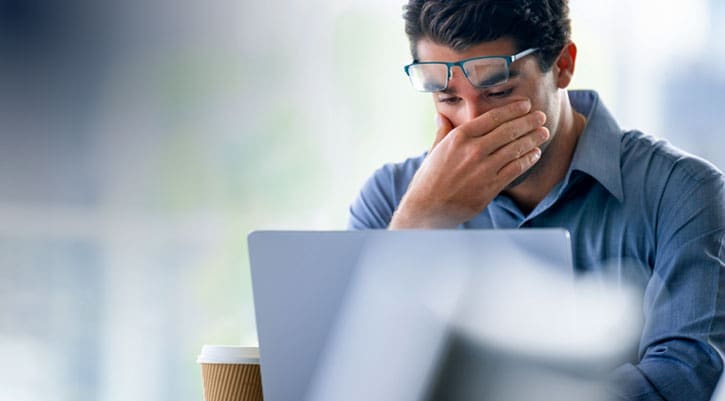 Stressed or tired businessman with laptop looking upset, sad or depressed